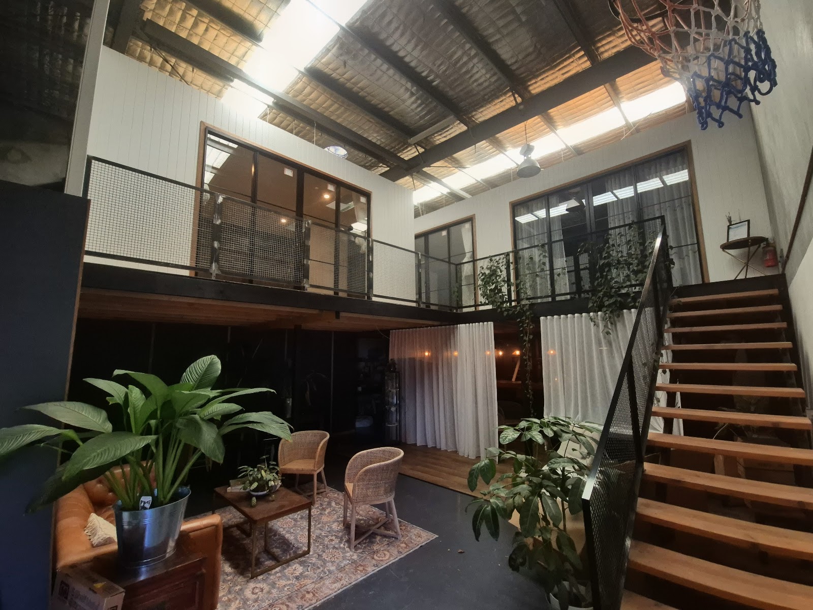 Industrial loft fit-out with a timber mezzanine, open stair and black mesh balustrade