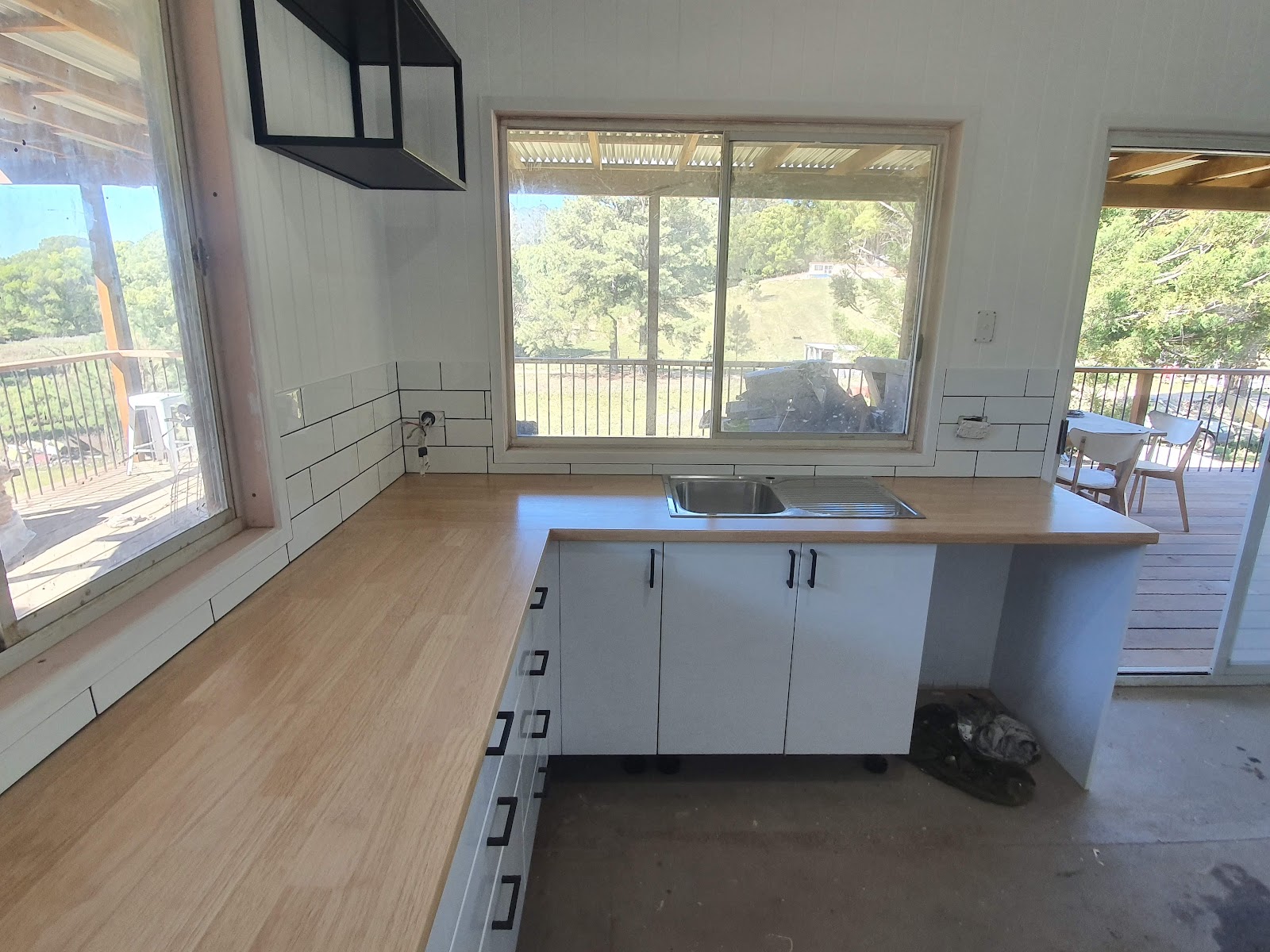 Kitchen in progress with a timber benchtop and white subway tile splashback