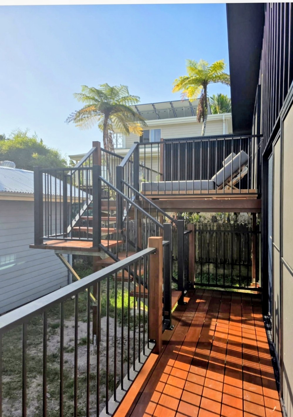 External timber stairs and landing with black balustrade and red hardwood decking